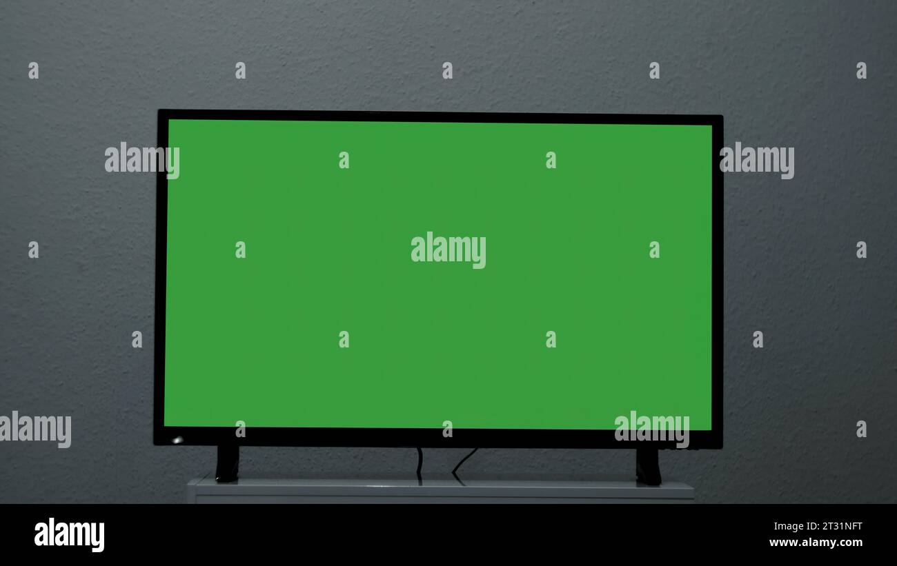 Plasma TV with green screen stands on background wall. Concept. Green ...