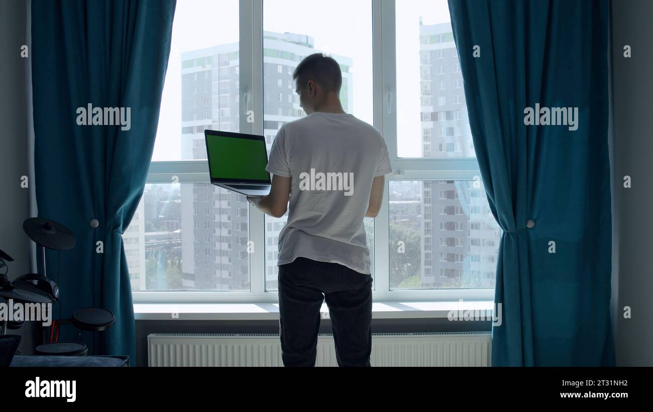 The screen in the laptop is green. Media. A man picking at a laptop with a green screen in front