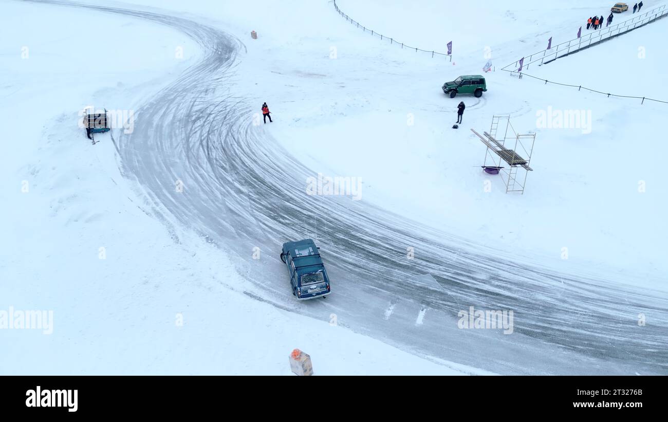 Aerial view of drifting cars on the snow covered off road. Clip. Winter race on a frozen lake. Stock Photo