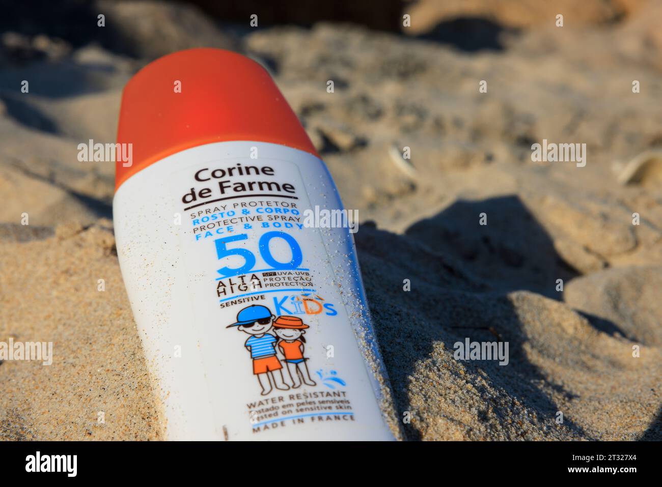 Sun cream bottle in the sand on the beach on Ilha do Farol (Lighthouse Island) off the coast of Olhão in Portugal. Stock Photo