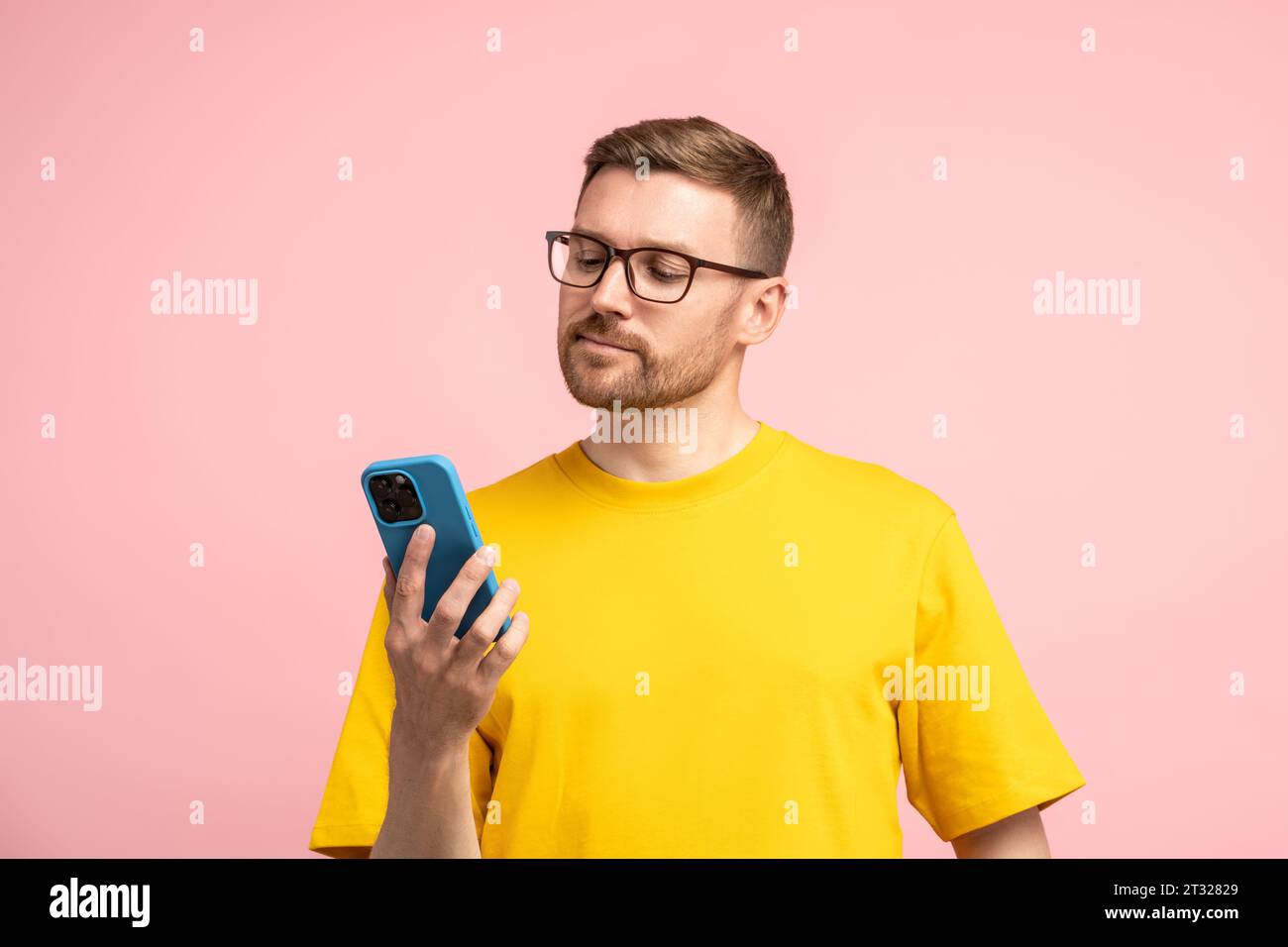 Calm bearded man in glasses looking at mobile phone screen with composed settled satisfied face  Stock Photo