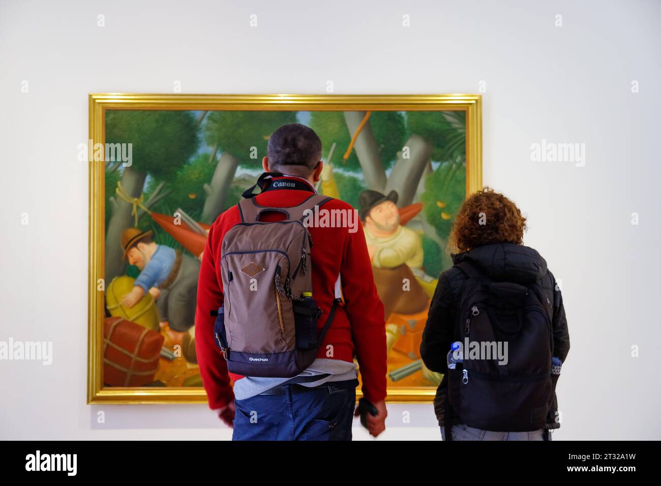 Bogota, Colombia - January 2, 2023: Couple of visitors look at the painting by Fernando Botero 'Guerrilla de Eliseo Velasquez' in the Botero Museum Stock Photo