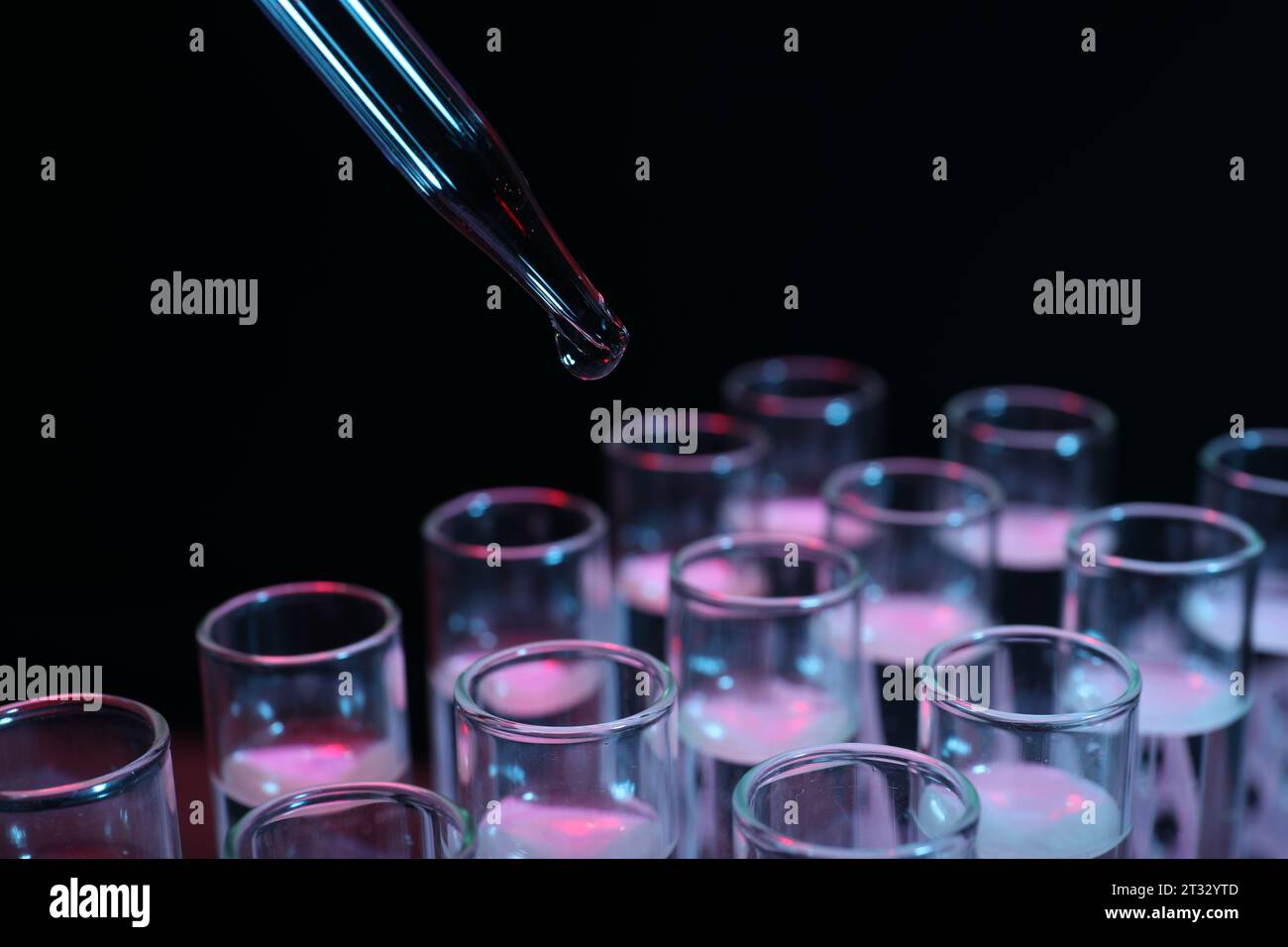 Dripping reagent into test tube on black background, closeup ...