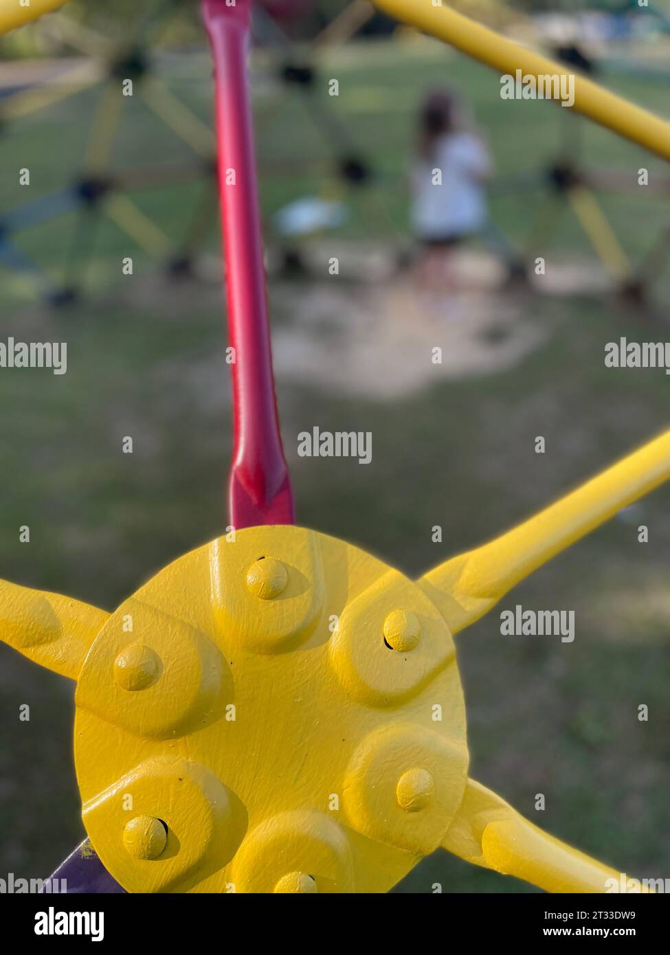 Yellow green and red monkey bars Toddler in distance playing at the