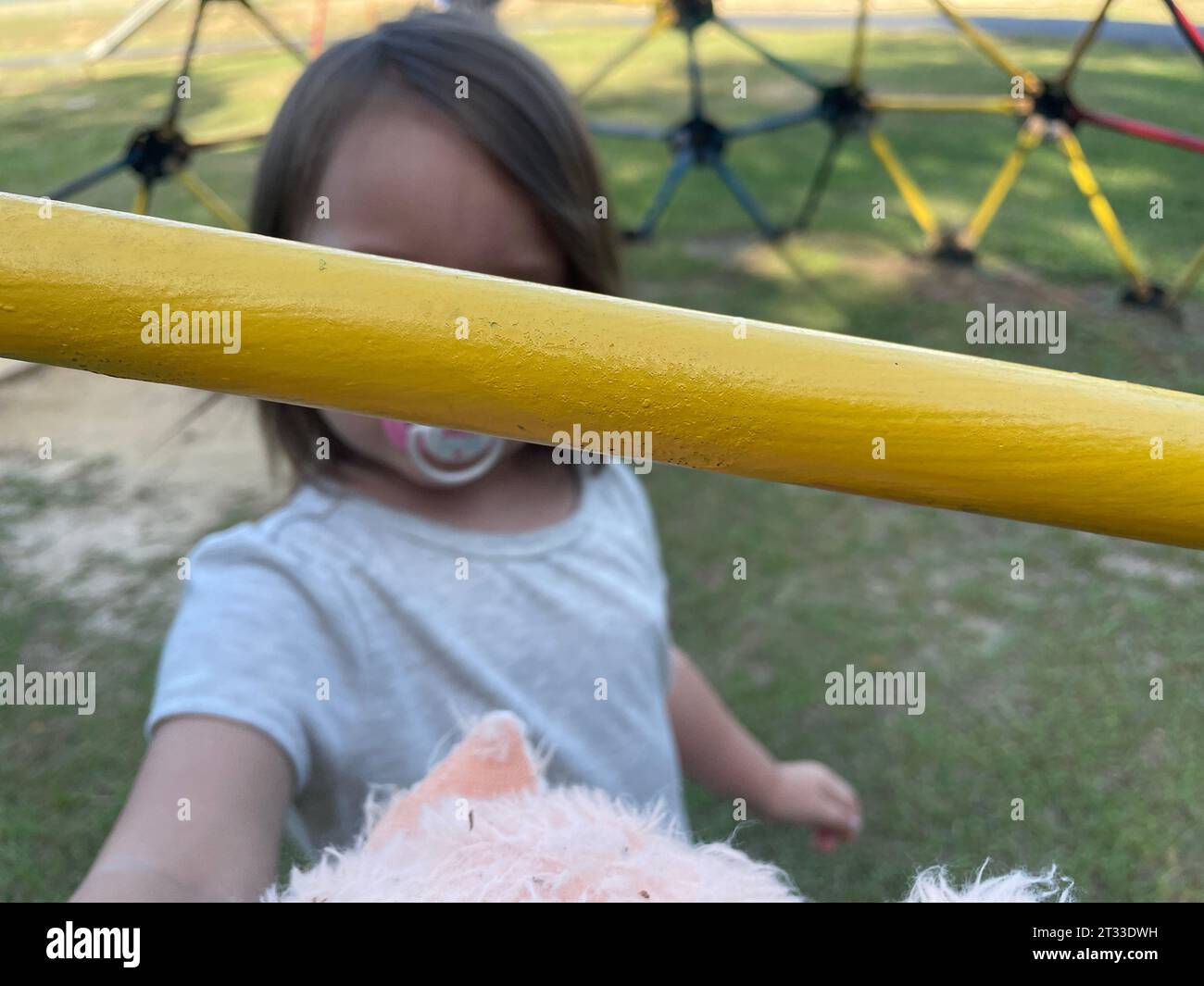 Yellow bar monkey bars Toddler playing at the park background Stock Photo
