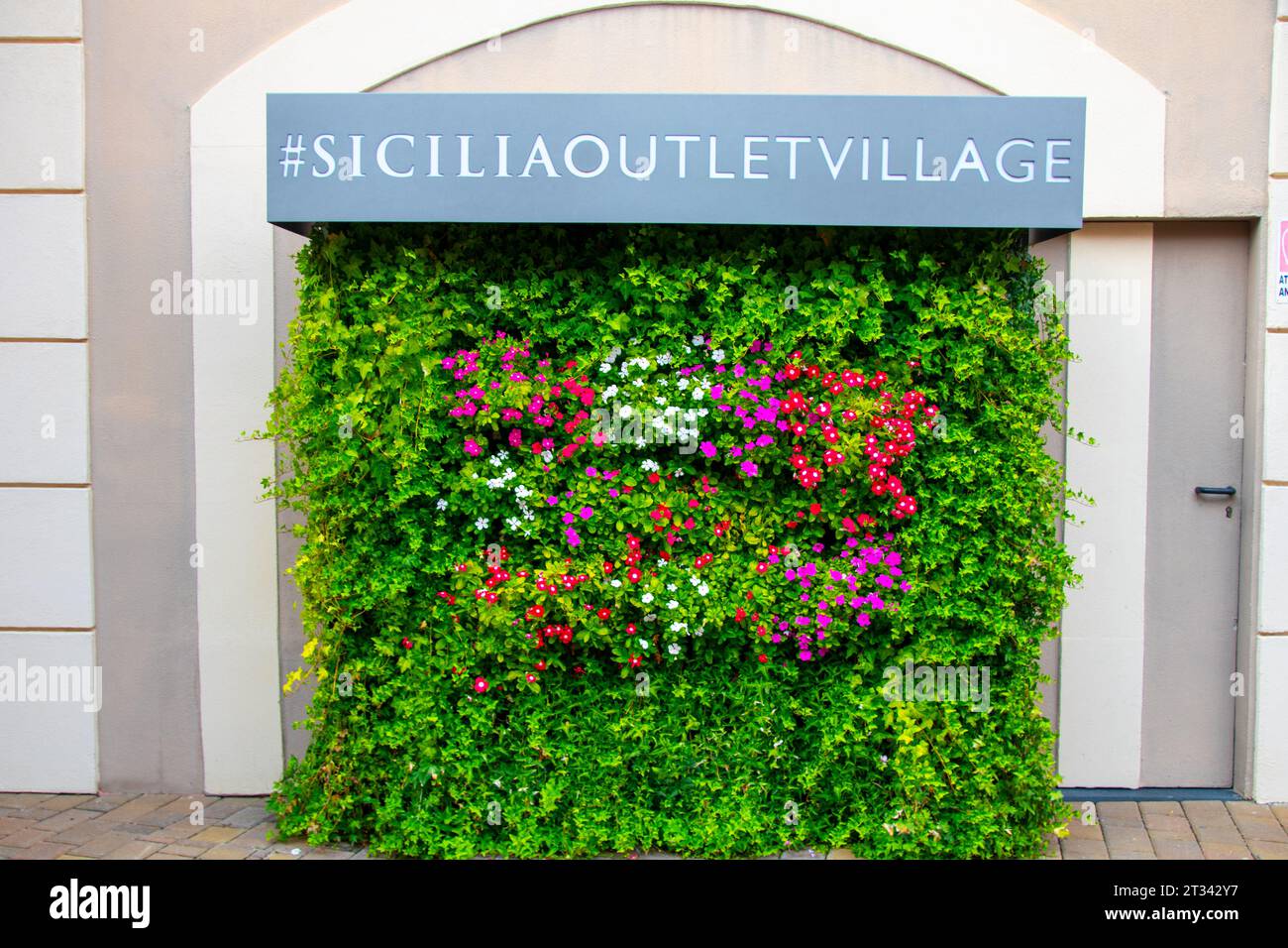 AGIRA, SICILY, Italy - 30 SEP 2023. Sicilia Outlet Village shopping centre is a popular visitor magnet for holidaymakers and locals alike. Flower adve Stock Photo