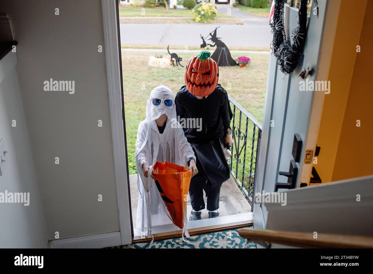 Trick or Treaters holding out candy bags at front door Stock Photo