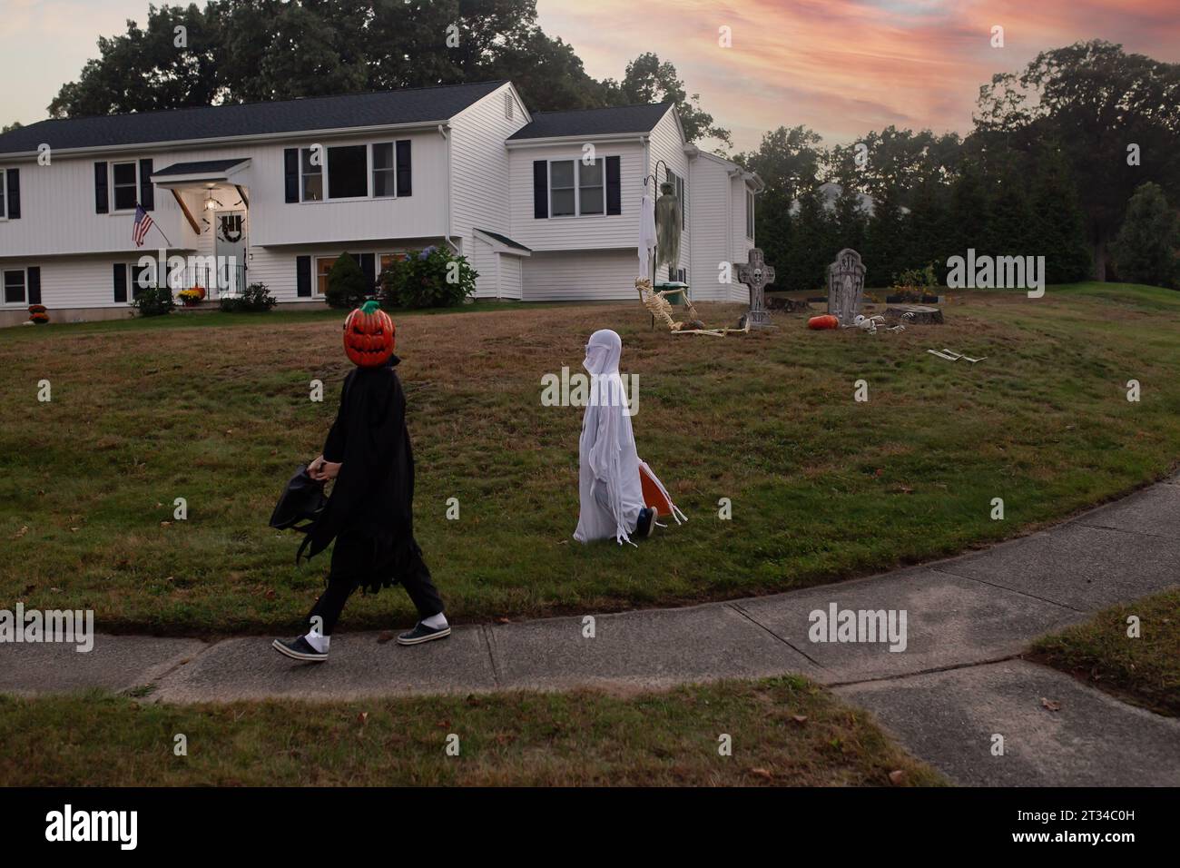 Kids dressed up in costumes for Halloween walking in a neighborhood Stock Photo