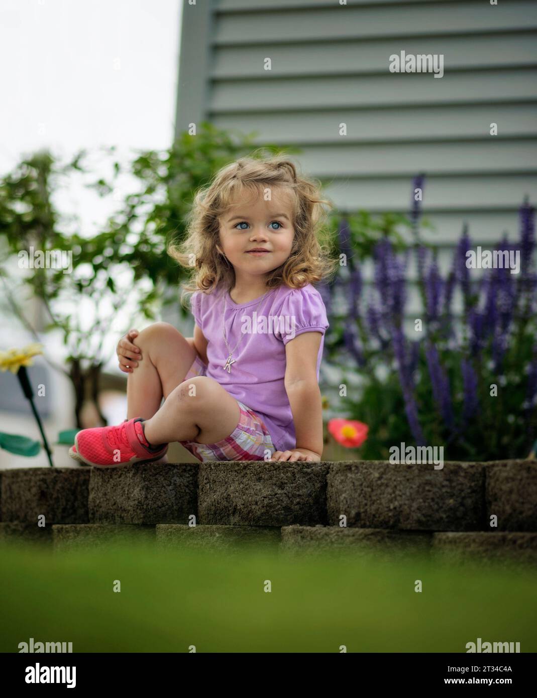 Little girl smiling in flower garden Stock Photo - Alamy