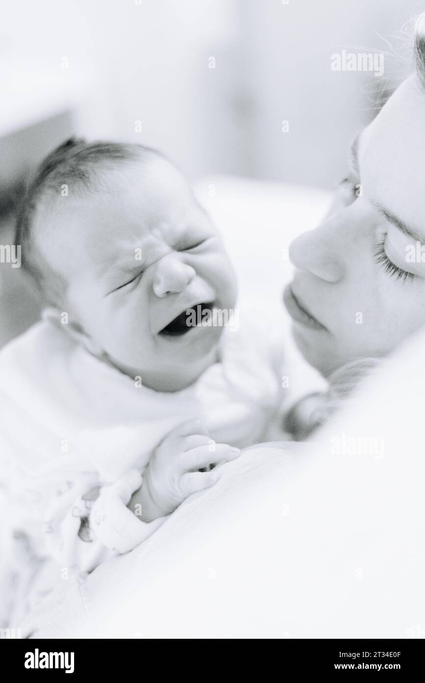 One week old newborn baby crying on his mothers shoulder Stock Photo