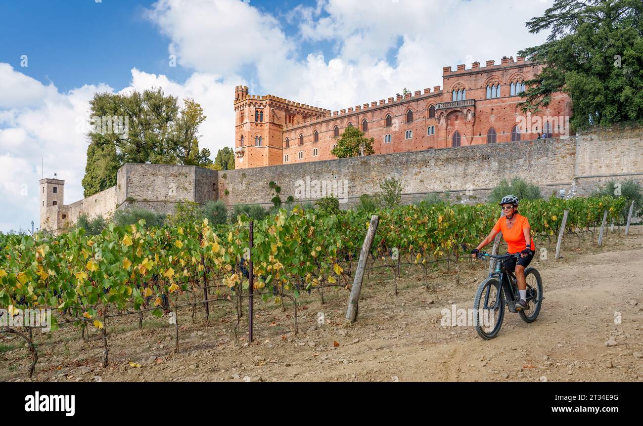 nice senior woman riding her electric mountain bike in the vineyards below Castello Brolio in the Ghianti Area of Tuscany,Italy Stock Photo