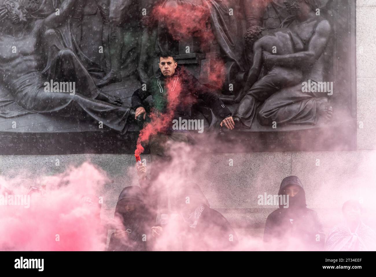 Protester enveloped in red smoke in Trafalgar Sq at a Free Palestine protest in London following the escalation of the conflict in Israel and Gaza Stock Photo