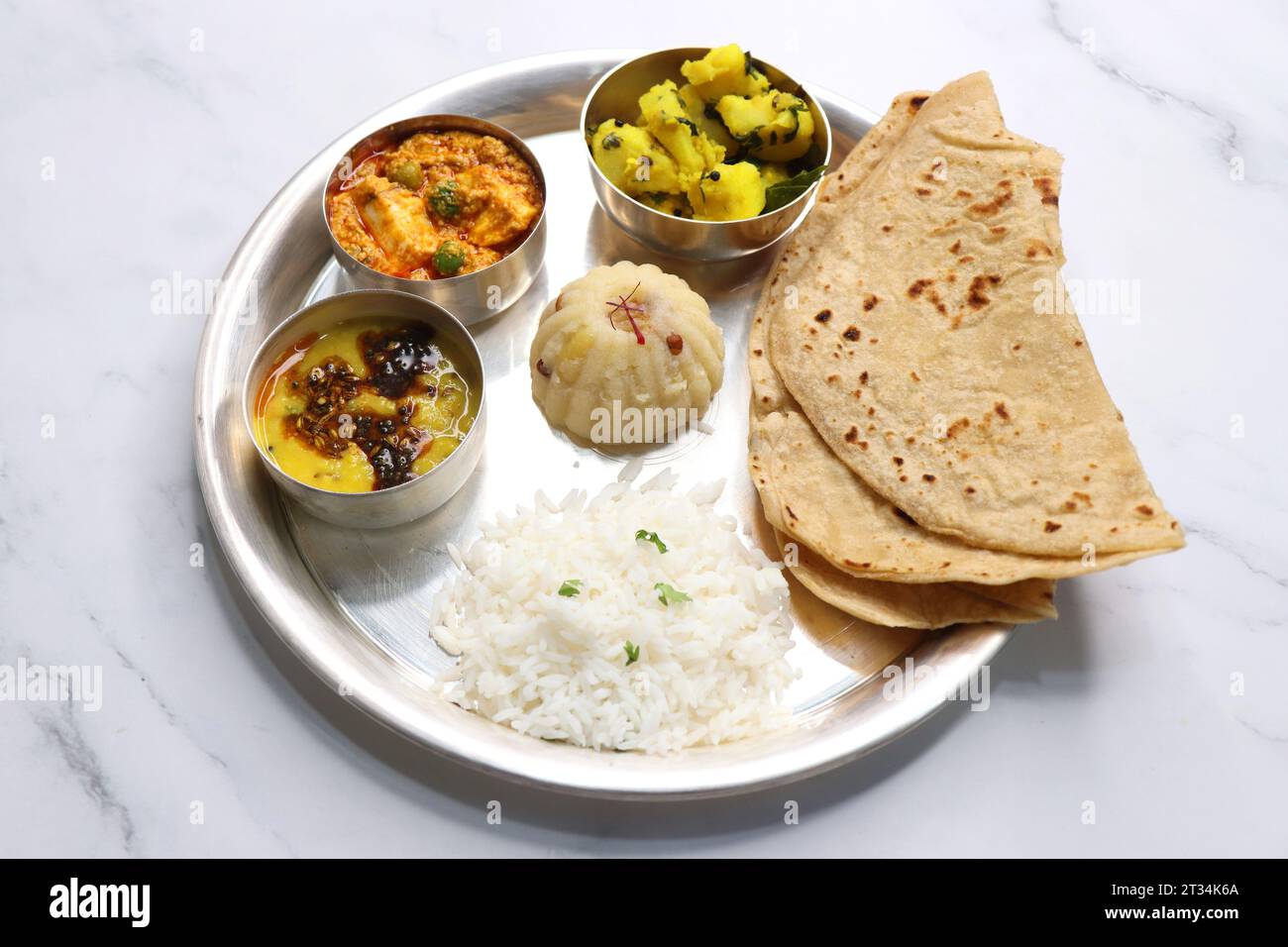 Indian vegetarian Thali or platter includes Aloo ki sabji, dal rice, Roti bhaji, Matar Paneer, Sheera or suji ka halwa, chapati. Indian food, sheera. Stock Photo