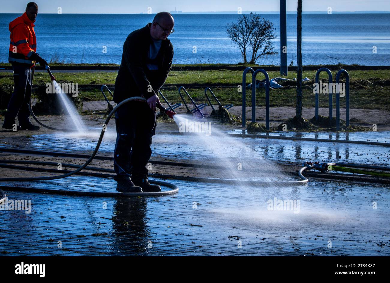 Stahlbrode, Germany. 23rd Oct, 2023. Employees of the municipality clean the parking areas and roads to the ferry terminal after the storm surge. Ferry service from the mainland to the island of Rügen is suspended. Along the Baltic coast, the damage is documented and initial repairs and reconstruction work are underway. Credit: Jens Büttner/dpa/Alamy Live News Stock Photo