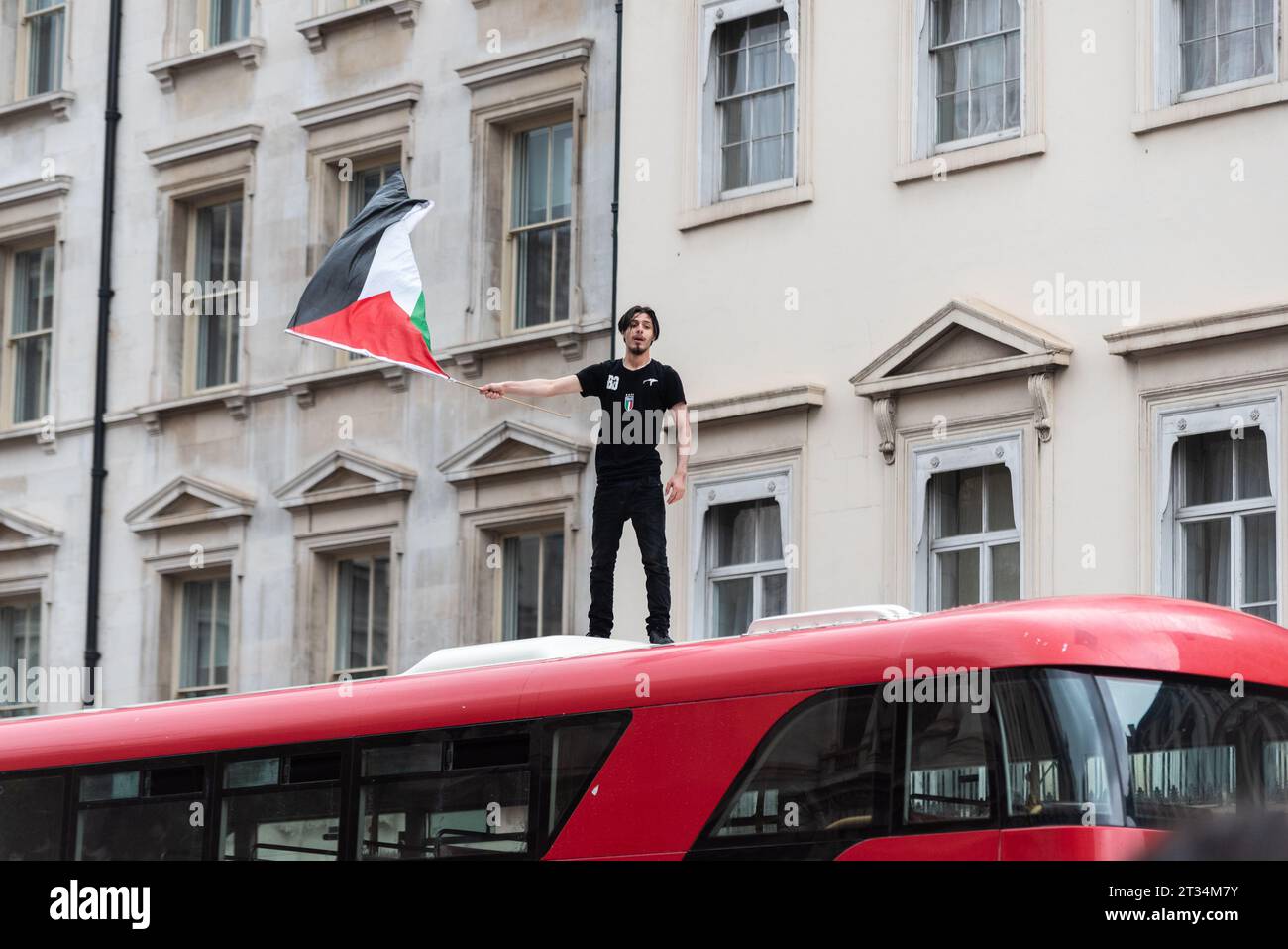 Protester on a London bus roof waving a flag at a Free Palestine