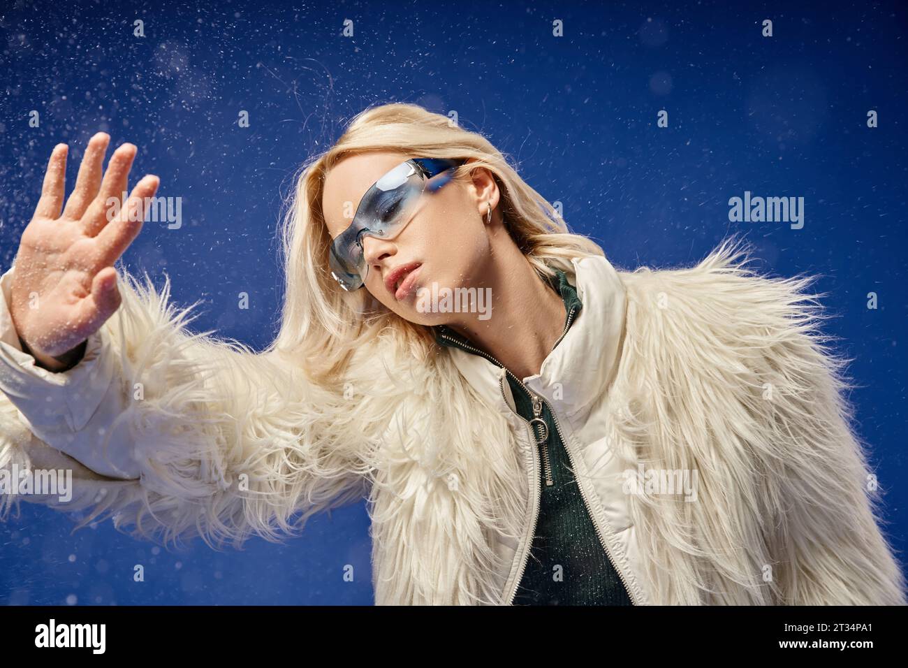 beautiful woman in faux fur jacket and sunglasses posing under falling ...