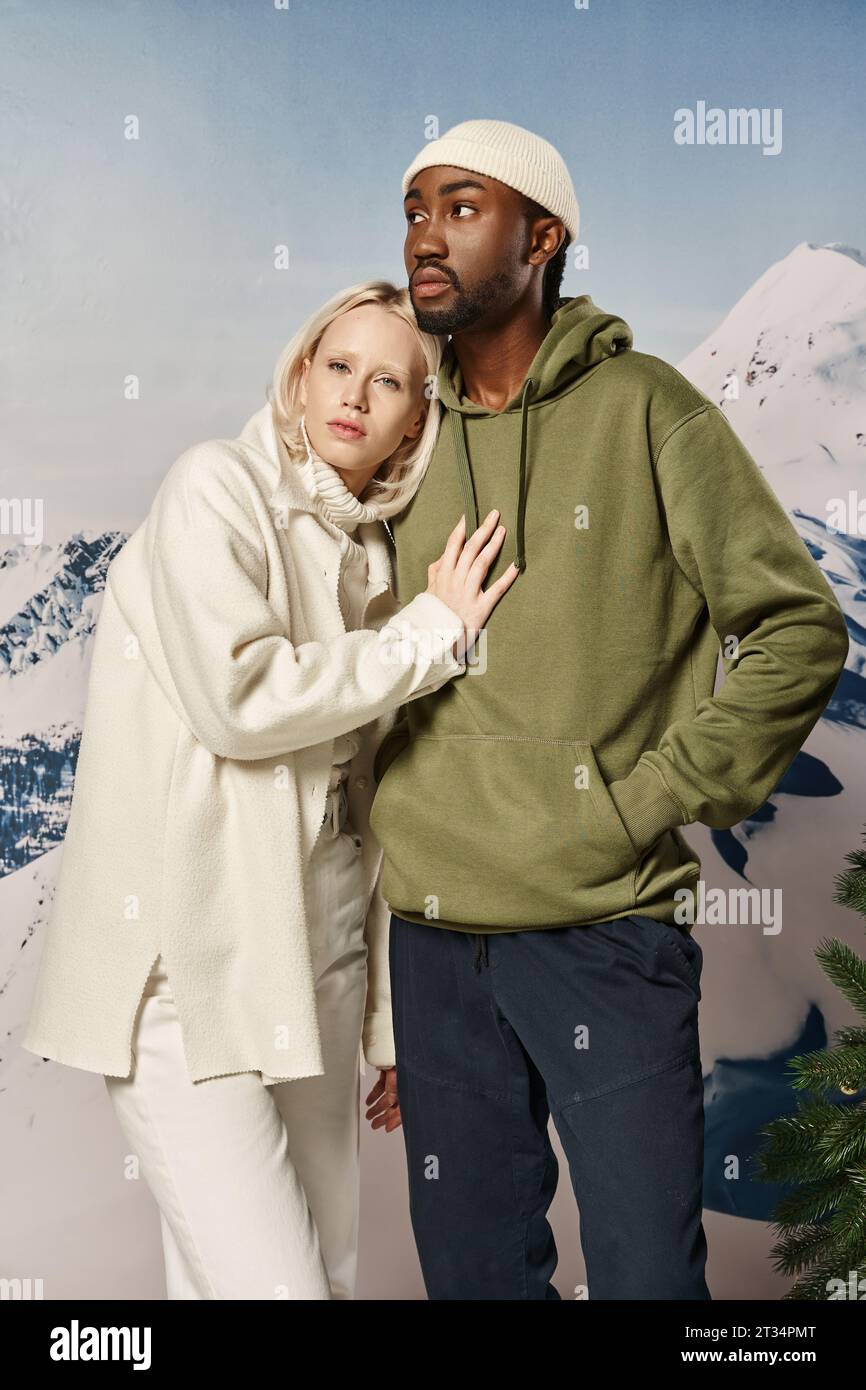 young blonde woman with her hand on her boyfriend chest with snowy backdrop, winter fashion Stock Photo