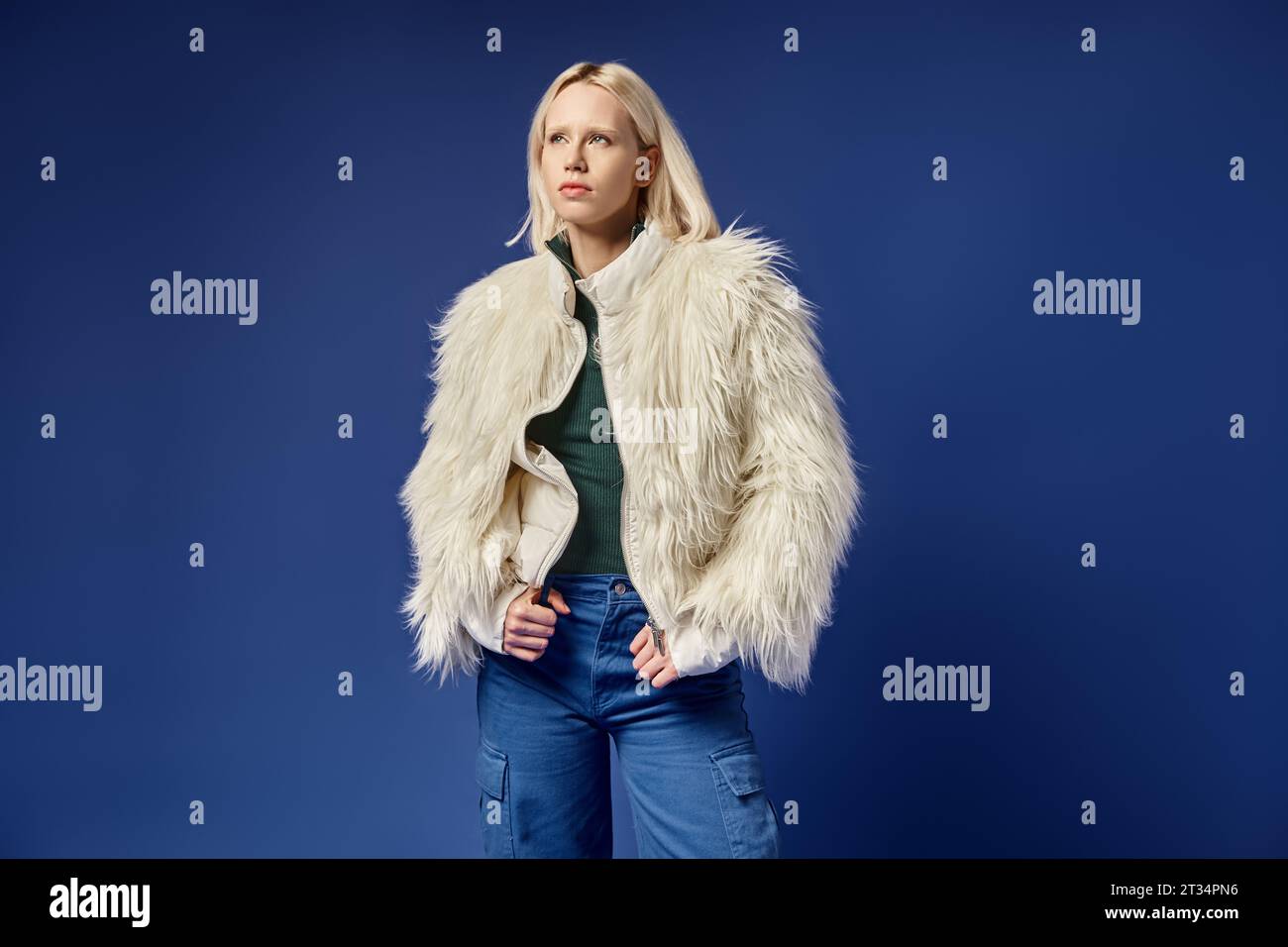 dreamy and stylish blonde woman in faux fur jacket and denim jeans ...