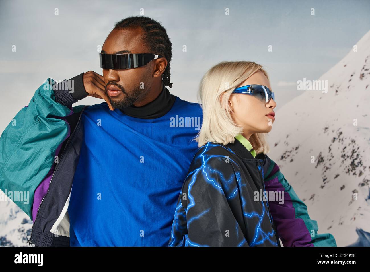 fashionable couple in stylish sunglasses posing together with mountain backdrop, winter concept Stock Photo