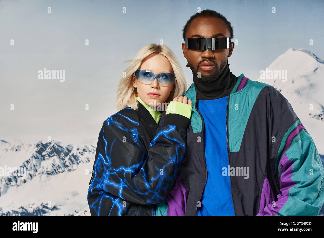 fashionable interracial couple in vibrant attire with sunglasses with snowy backdrop, winter concept Stock Photo