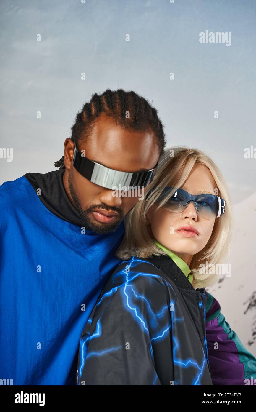 close up of stylish couple in vibrant sunglasses hugging and looking at camera, winter concept Stock Photo