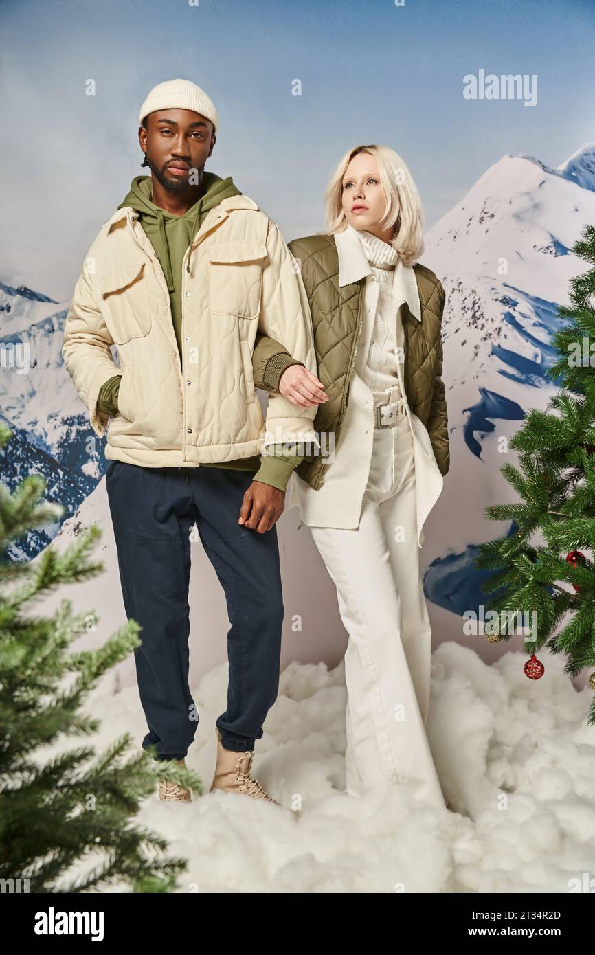 beautiful multicultural couple in warm stylish clothes posing with hand on arm, winter concept Stock Photo