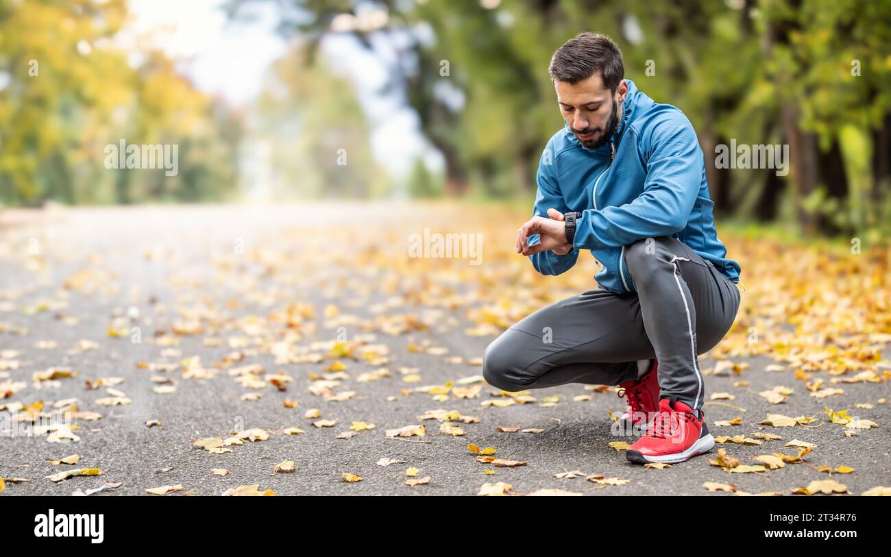 A good-looking athlete puts on his sports watch before running. Copy space on the left side. Stock Photo