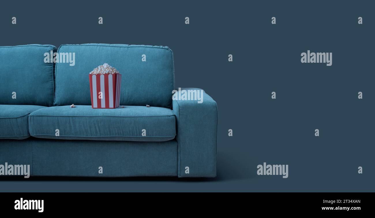 Popcorn box on the couch: TV, movies and entertainment concept Stock Photo