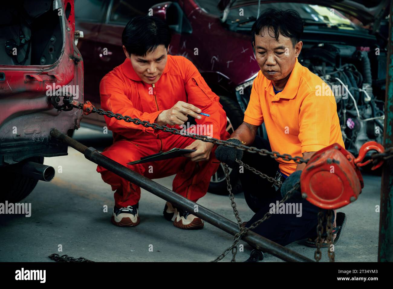 Mechanic testing strength and reliability of chain hoist for car towing