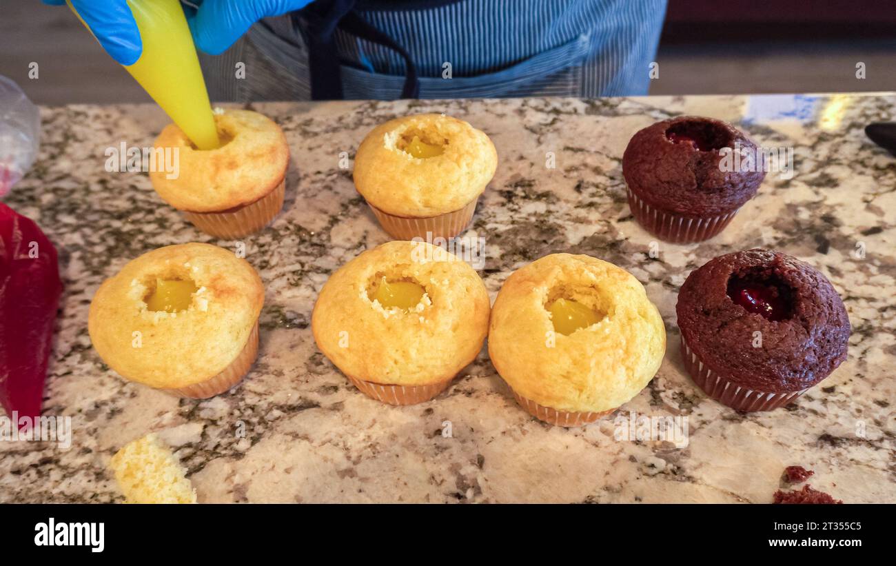 Filling Vanilla, Chocolate Cupcakes with Lemon, Raspberry Stock Photo