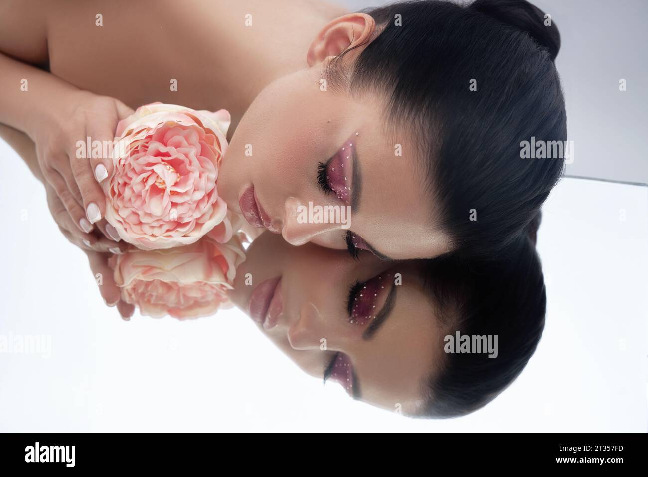 Beauty portrait of a woman lying on the floor, pink makeup and flowers, clean skin, natural cosmetics, spa treatments Stock Photo