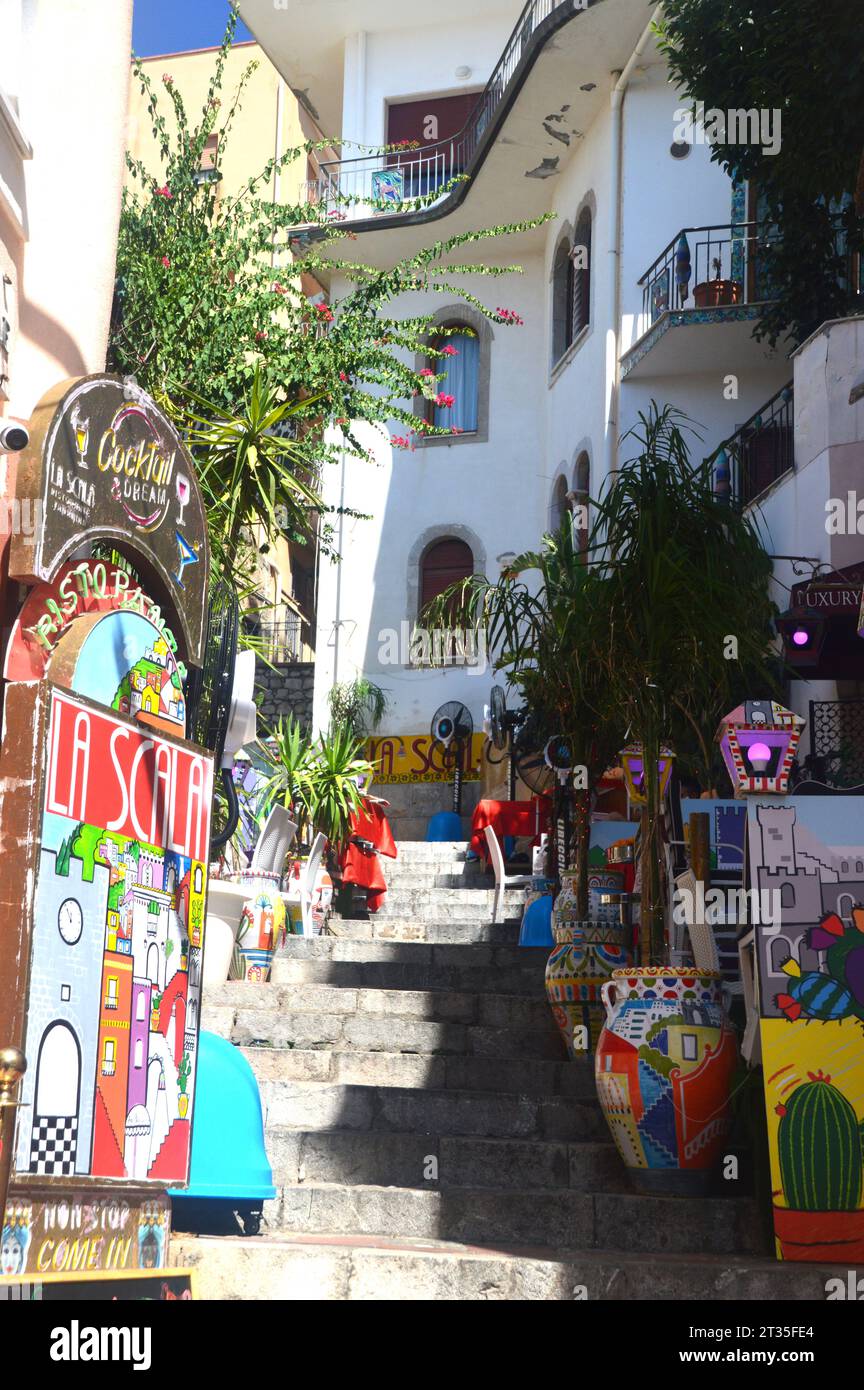 Brightly Coloured Artwork up Stone Steps Outside in Narrow Street by a Traditional Sicilian Restaurant in Taormina, Sicily, EU. Stock Photo