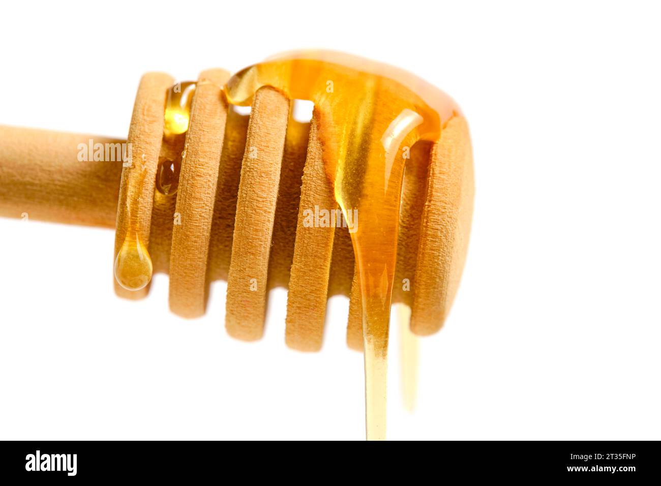 Liquid and fresh honey dripping from wooden honey spoon white background Stock Photo
