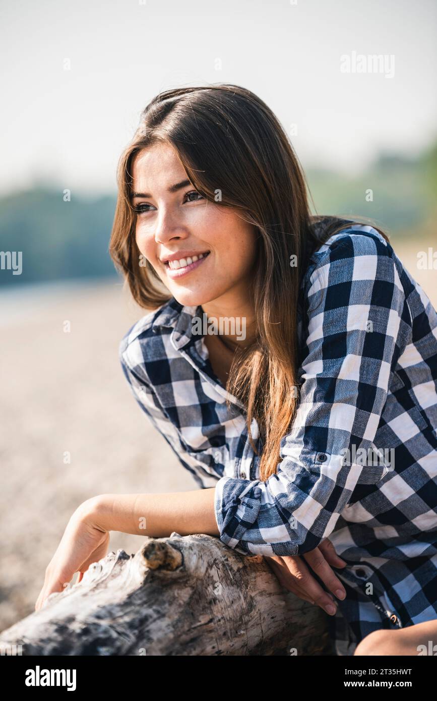 Smiling young woman sitting outdoors Stock Photo