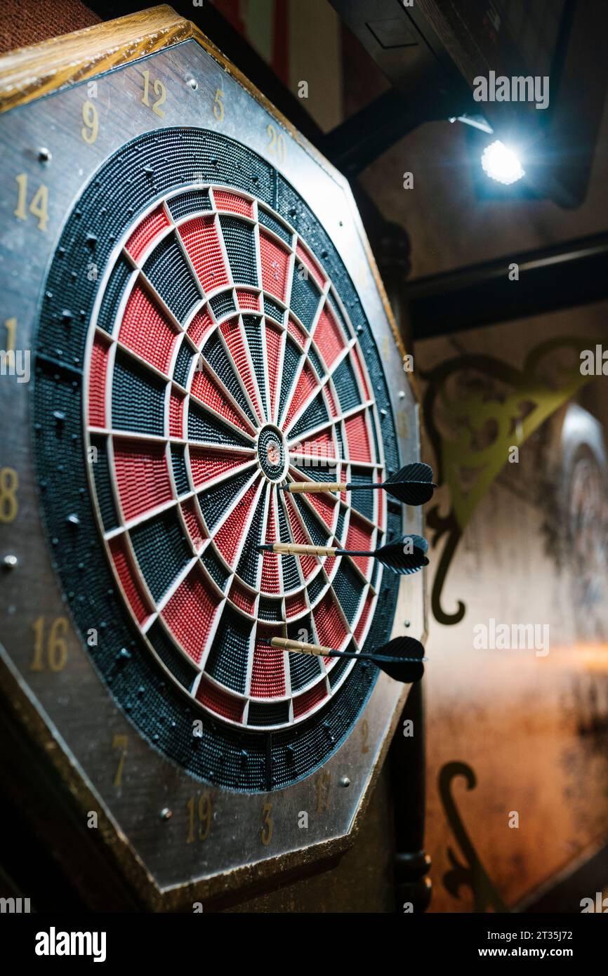 Darts hitting target on dartboard in bar Stock Photo