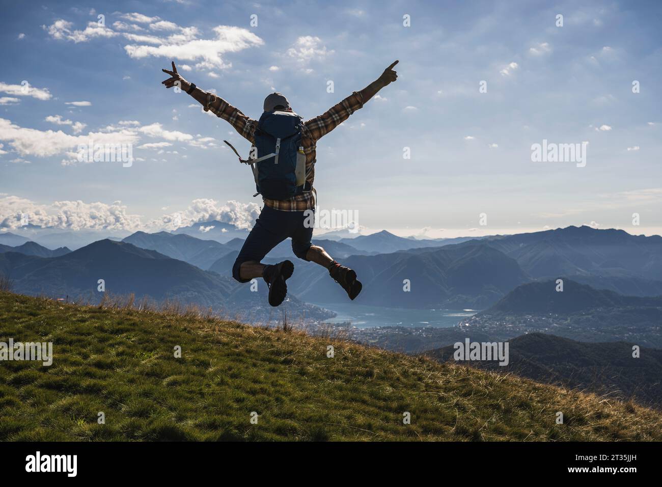 Happy hiker jumping with arms raised on mountain Stock Photo - Alamy