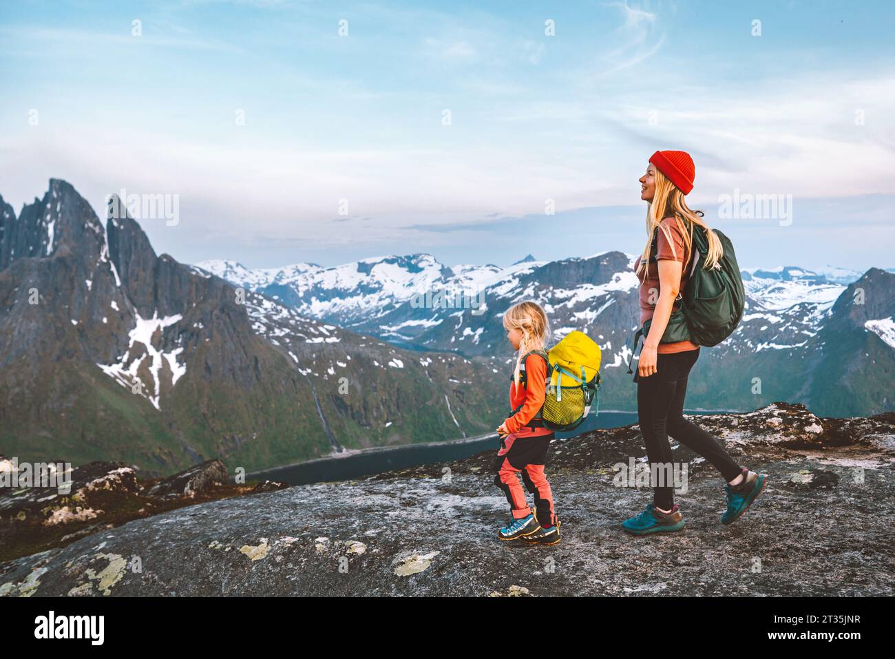 Norway adventure travel family vacation: Mother and child with backpacks hiking Senja island scenic mountain trails eco-tourism healthy lifestyle acti Stock Photo
