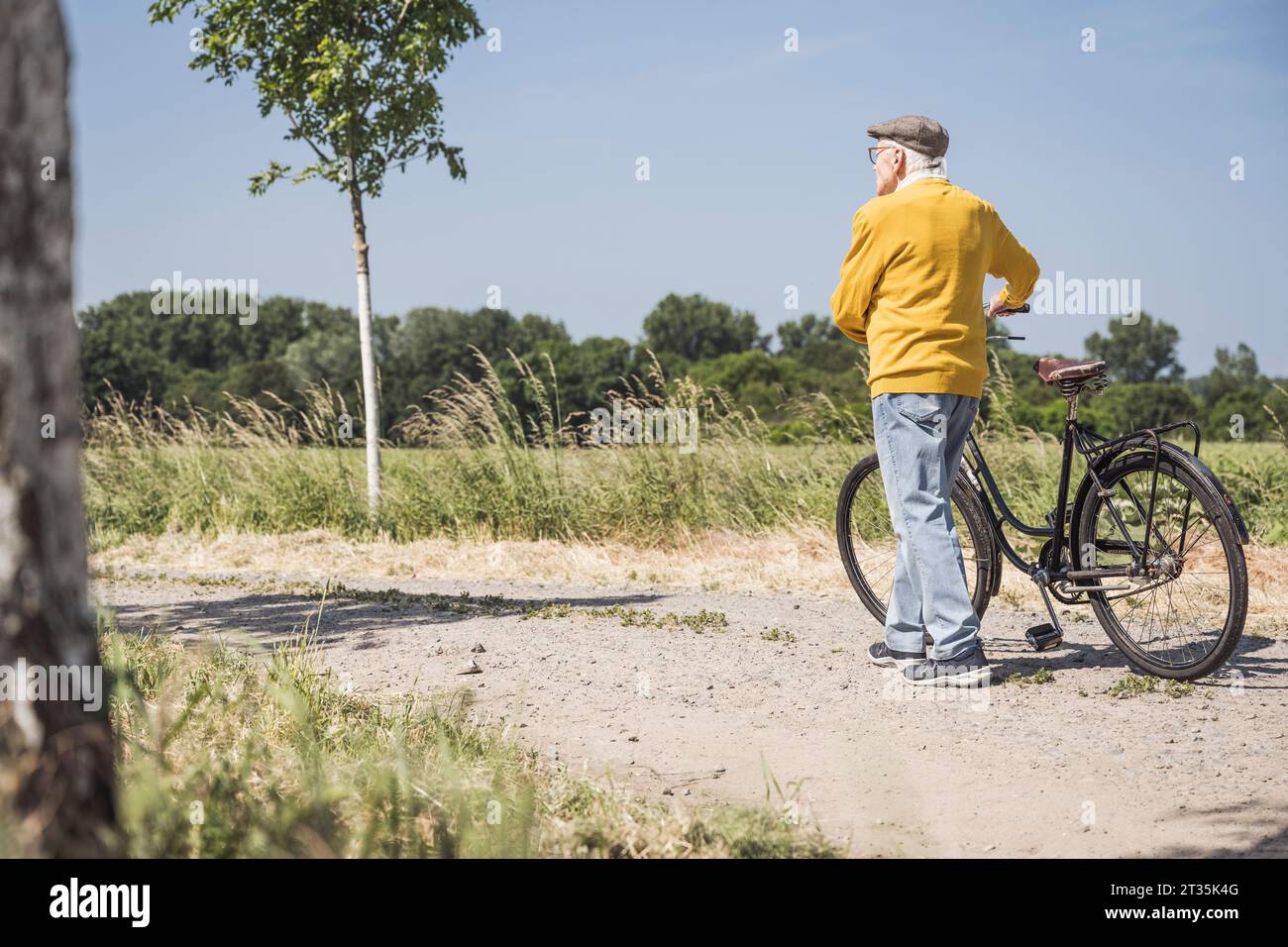 Active senior man walking with bicycle on road Stock Photo