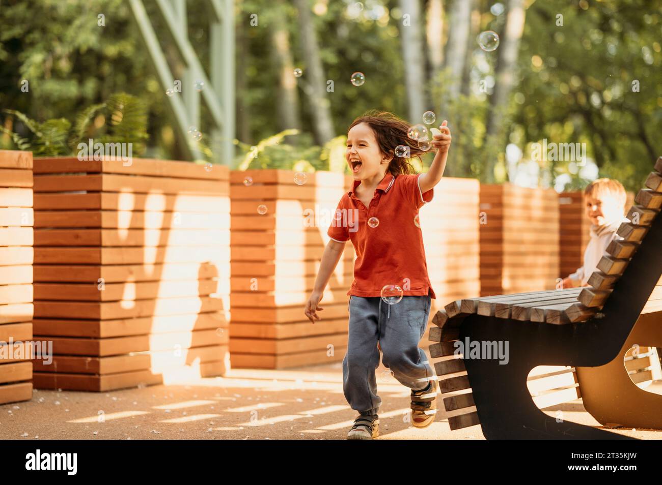 Carefree boy playing with bubbles in park Stock Photo