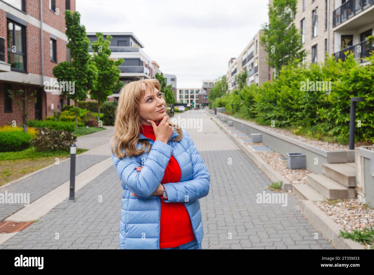Contemplative woman standing near residential area Stock Photo