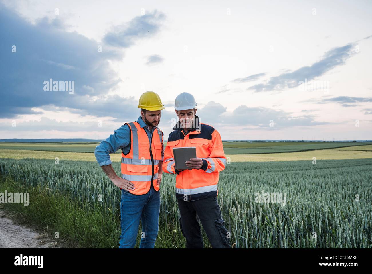 Engineers using tablet PC discussing at field Stock Photo