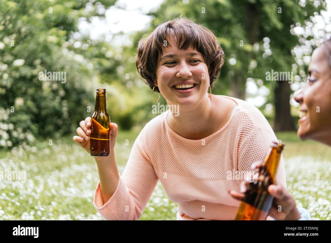 Happy women holding beer in park Stock Photo