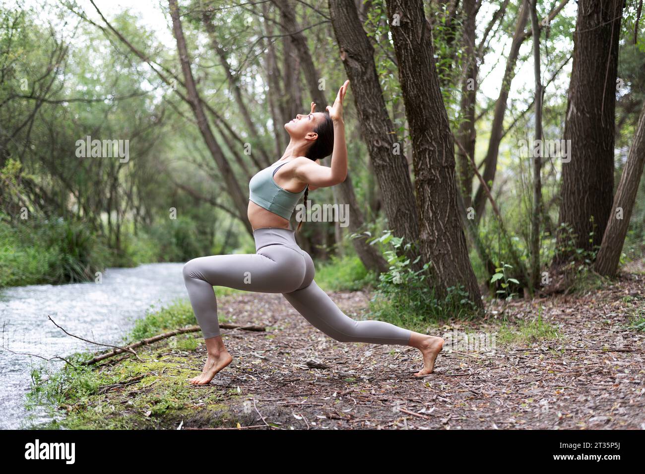 Woman practicing Pilates near stream at forest Stock Photo