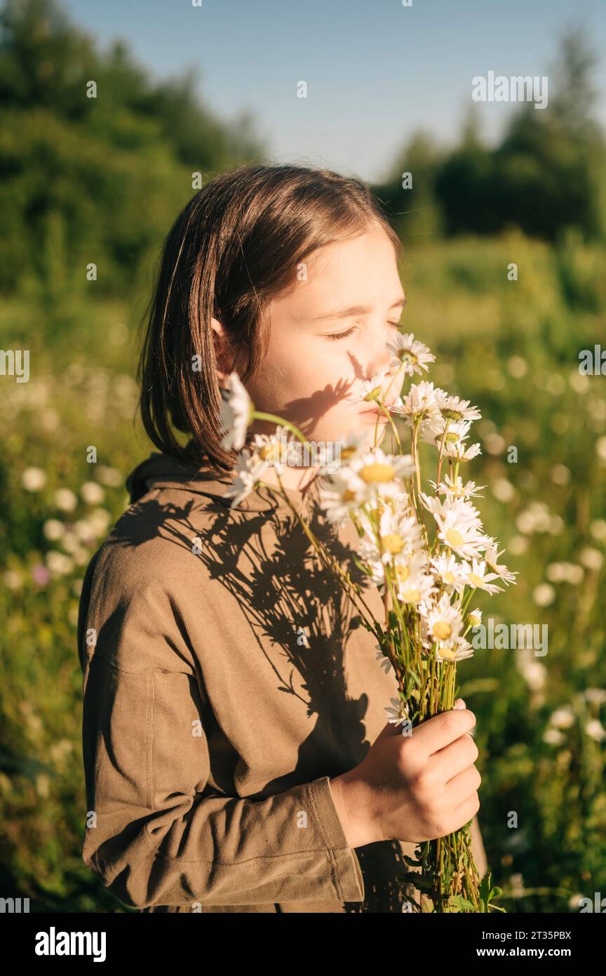 Boy with eyes closed smelling bunch of daisies in field Stock Photo - Alamy