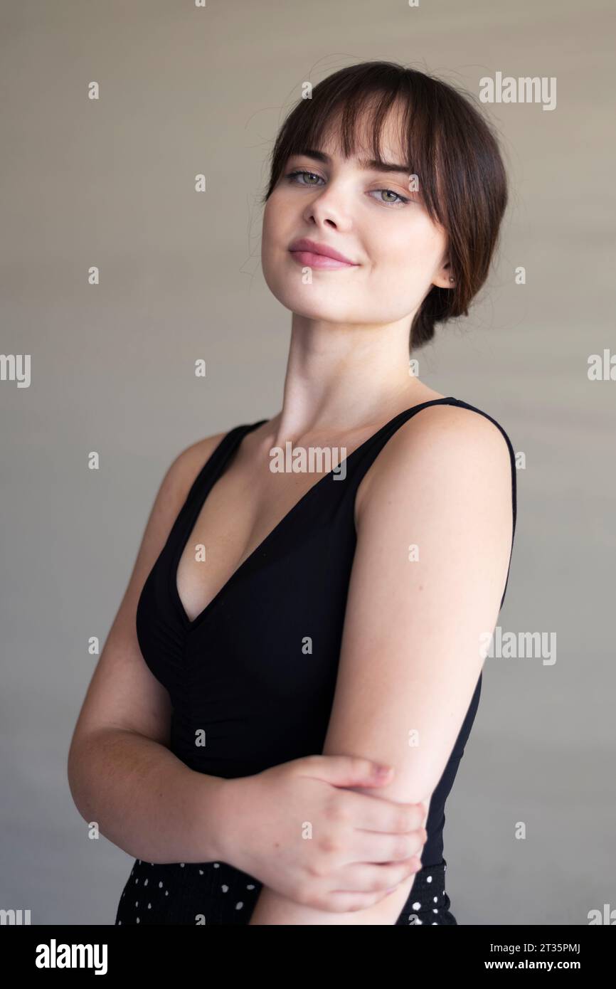Smiling beautiful woman standing in front of wall Stock Photo - Alamy
