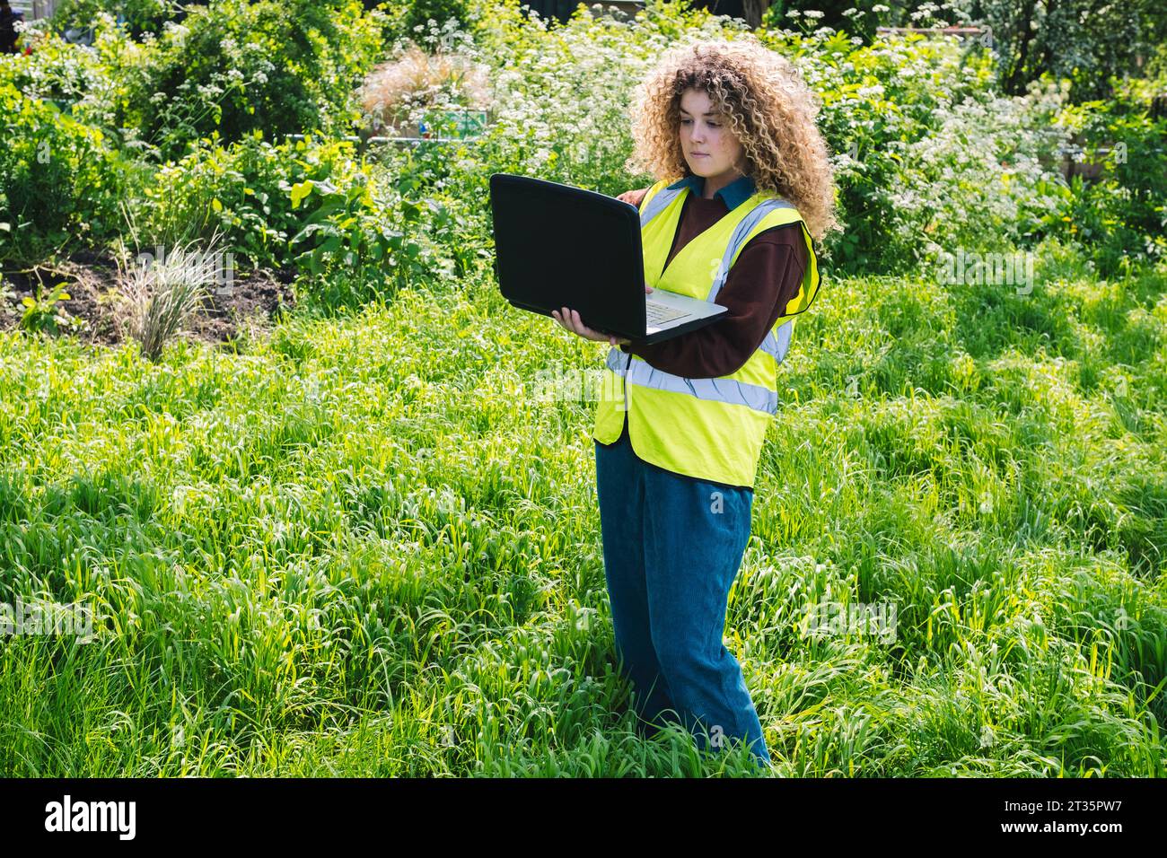 Engineer using laptop standing on grass Stock Photo