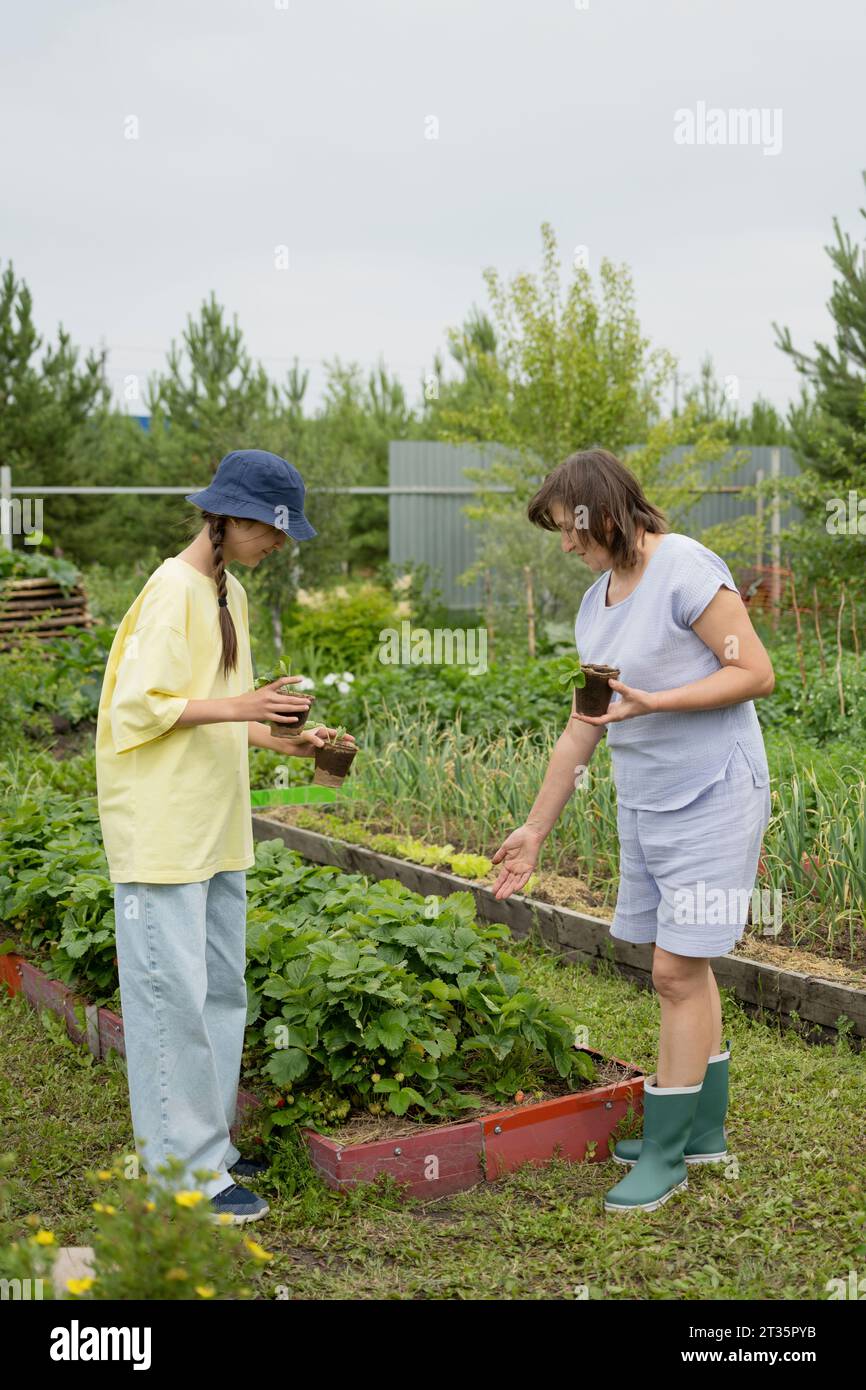 Mother and daughter holding potted plant in garden Stock Photo - Alamy