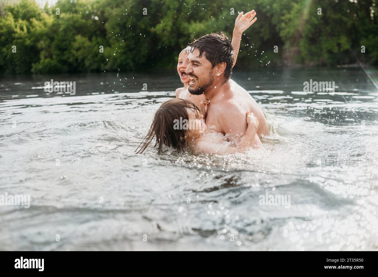 Cheerful father having fun with sons in water Stock Photo