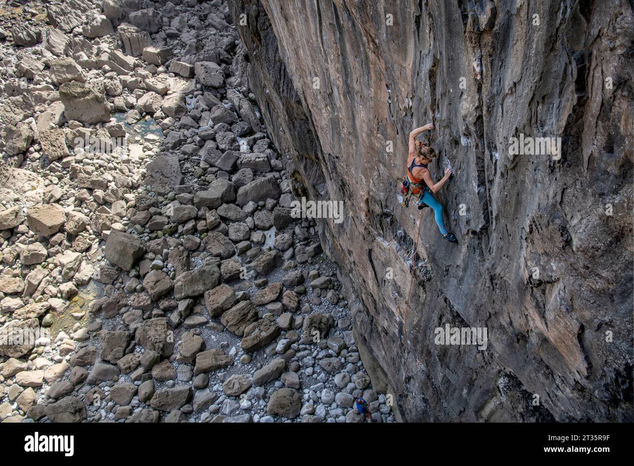 Determined woman climbing mountain using rope Stock Photo