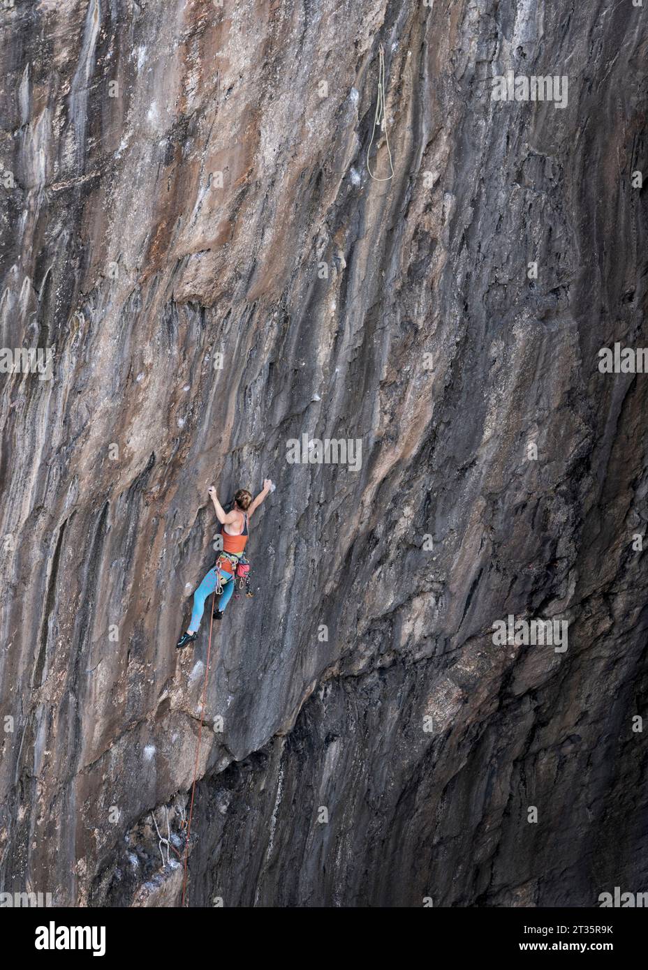 Woman climbing mountain with rope Stock Photo